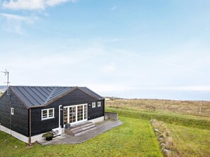 A black building with a sloped roof, a large glass door, and a small porch. - 4 Star Holiday Home in Juelsminde (Juelsminde)