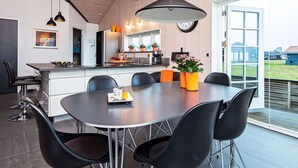 Una cocina moderna con zona de comedor, que cuenta con un amplio ventanal, un reloj y una lámpara colgante.