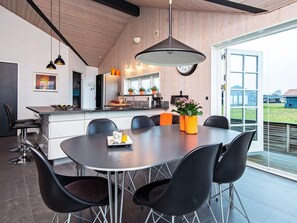 A modern kitchen with a dining area, featuring a large window, a clock, and a pendant light. - 4 Star Holiday Home in Juelsminde (Juelsminde)