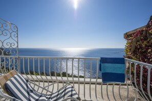 A balcony with a view of the sea, a striped chair, and a blue towel. - Il Barilotto (Positano)