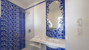 A bathroom with a shower, a sink, a mirror, and a hairdryer. - Il Barilotto (Positano)