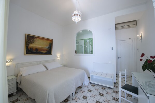Une chambre à coucher comprenant un lit, une table de chevet, un bureau, une chaise, un miroir et un lustre.
