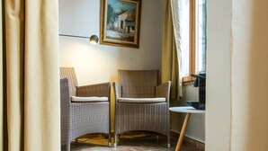 Une pièce d’angle meublée de mobilier en osier, avec un tableau au mur et une fenêtre agrémentée de rideaux.