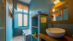 Une salle de bain avec une baignoire, un lavabo, une fenêtre et un miroir.