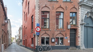 Une rue pavée, avec un bâtiment en briques rouges, un vélo et un panneau indiquant une distance de 3,5 km.