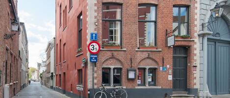 A cobblestone street with a red brick building, a bicycle, and a sign indicating a 3.5 km distance.
