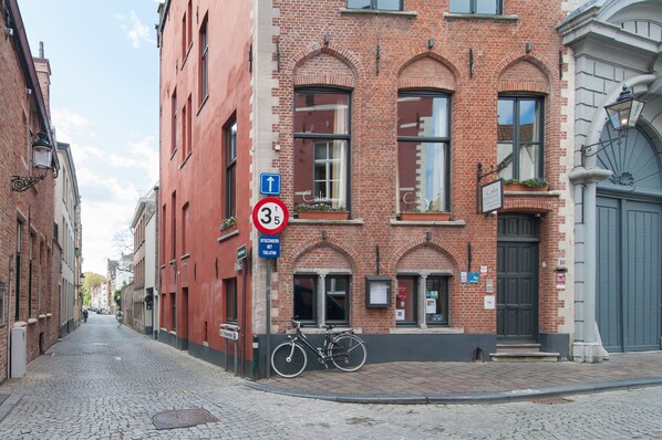 Una calle empedrada con un edificio de ladrillo rojo, una bicicleta y un letrero que indica una distancia de 3.5 km.