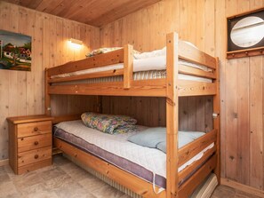 A bunk bed with a lower bunk, a wooden nightstand with drawers, and a wall-mounted lamp. - 5 Person Holiday Home in Fjerritslev (Fjerritslev)