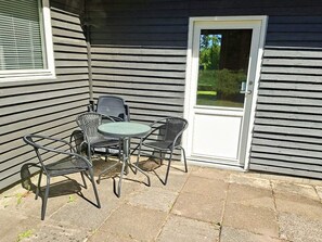 A patio with a table and four chairs, a door, and a window with blinds.