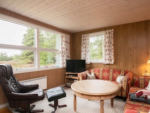 A cozy living room with a leather chair, a sofa, a round wooden table, and a television. - 5 Person Holiday Home in Fjerritslev (Fjerritslev)