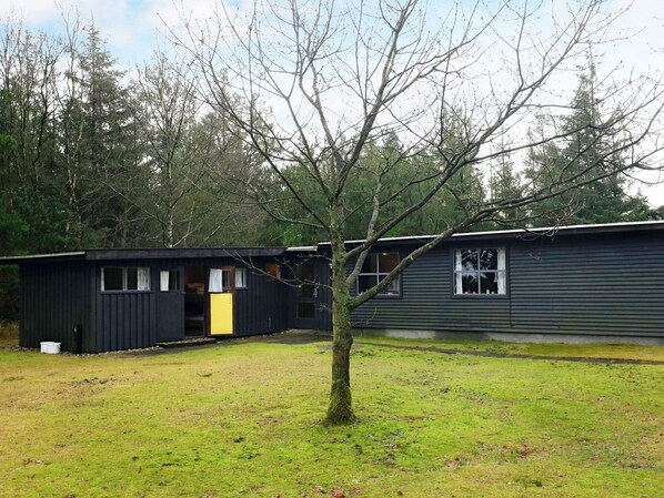Une cabane avec un petit porche et un arbre devant.