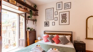 Habitación de hotel ordenada con cama, mesitas de noche, un espejo y vistas al balcón exterior.