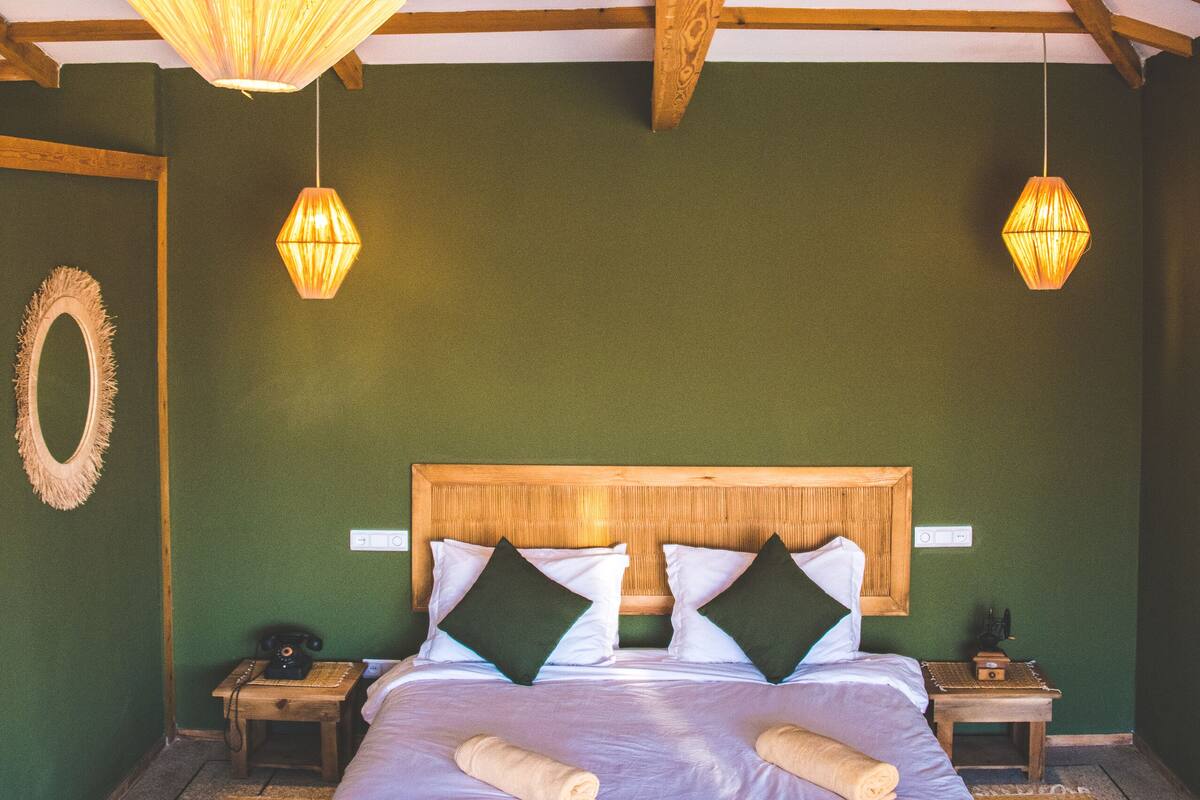Un dormitorio con estructura de cama de madera, dos mesitas de noche y una lámpara colgante.