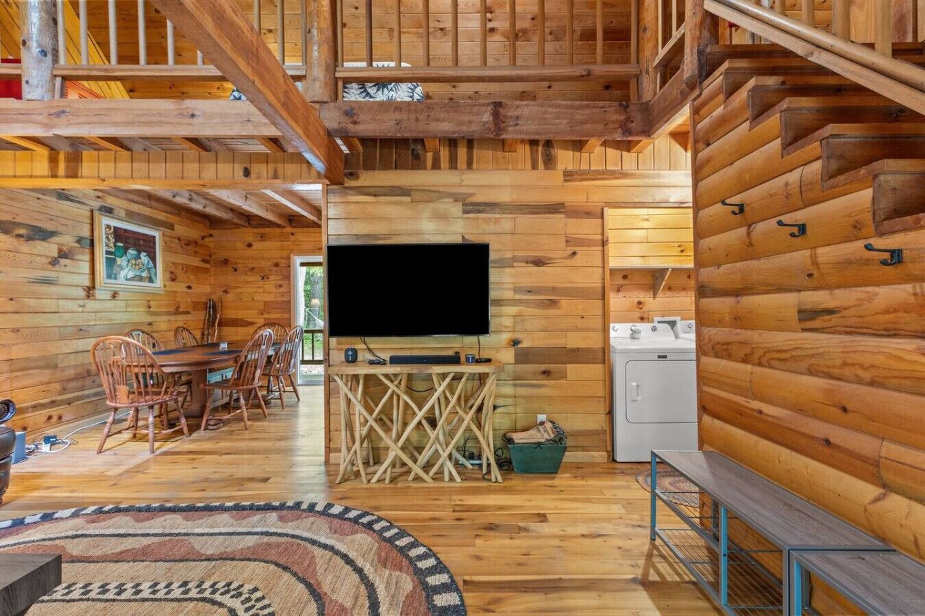 A wooden cabin interior with a dining area, a TV, and a washing machine.