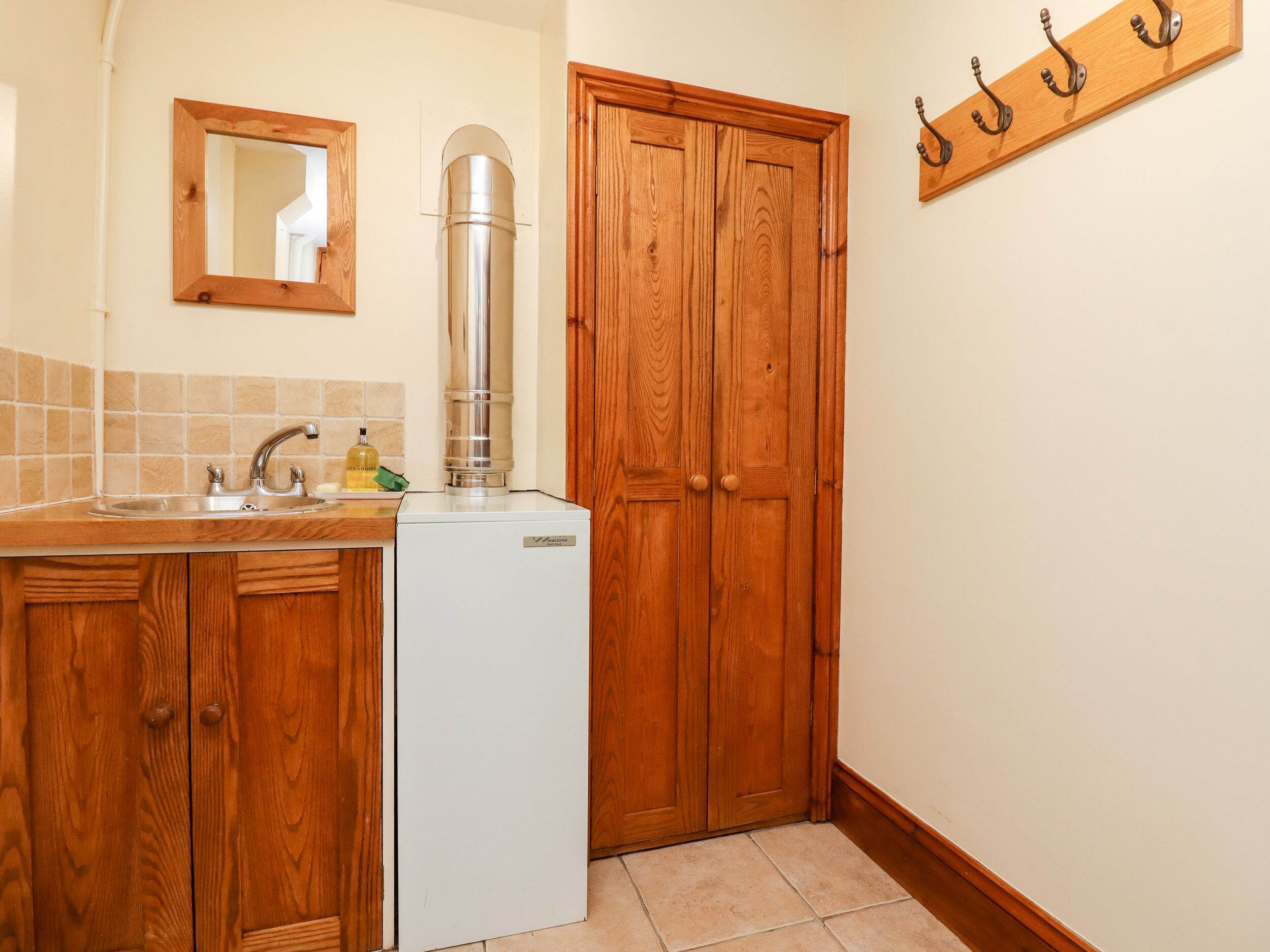 Una cucina con mobili in legno, un frigorifero bianco, un lavello e uno specchio.