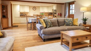 A cozy living room with a sofa, a coffee table, and a dining area with a table and chairs. - Little Orchard (Newton Abbot)