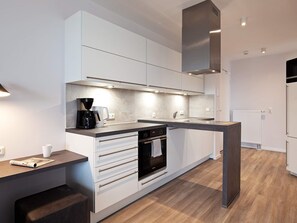 A modern kitchen with white cabinetry, a built-in oven, and a coffee maker.