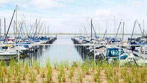 A marina with boats docked, surrounded by sand and grass. - 5 Star Holiday Home in Wendtorf (Wendtorf)