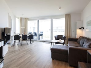 A modern living room with a sofa, a dining area with chairs, and a television. - 5 Star Holiday Home in Wendtorf (Wendtorf)