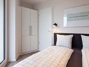 A bedroom with a bed, a wardrobe, a wall-mounted light, and a framed text on the wall. - 5 Star Holiday Home in Wendtorf (Wendtorf)