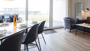 A modern dining area with a large table, chairs, and a bottle of wine. - 5 Star Holiday Home in Wendtorf (Wendtorf)
