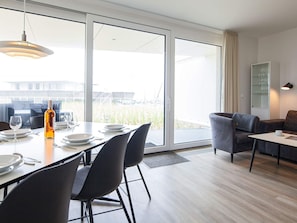 Uma sala de jantar moderna com uma mesa grande, cadeiras e uma garrafa de vinho.