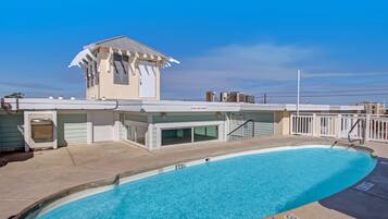 Une piscine à l’eau d’un bleu cristallin, un espace abrité avec une petite structure en forme de tour, et une clôture blanche qui entoure la piscine.