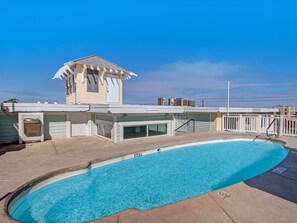A swimming pool with a clear blue water surface, a covered area with a small tower-like structure, and a white fence surrounding the pool. - Rooftop Pool Access, Walk to Beach and Tybrisa (Tybee Island)