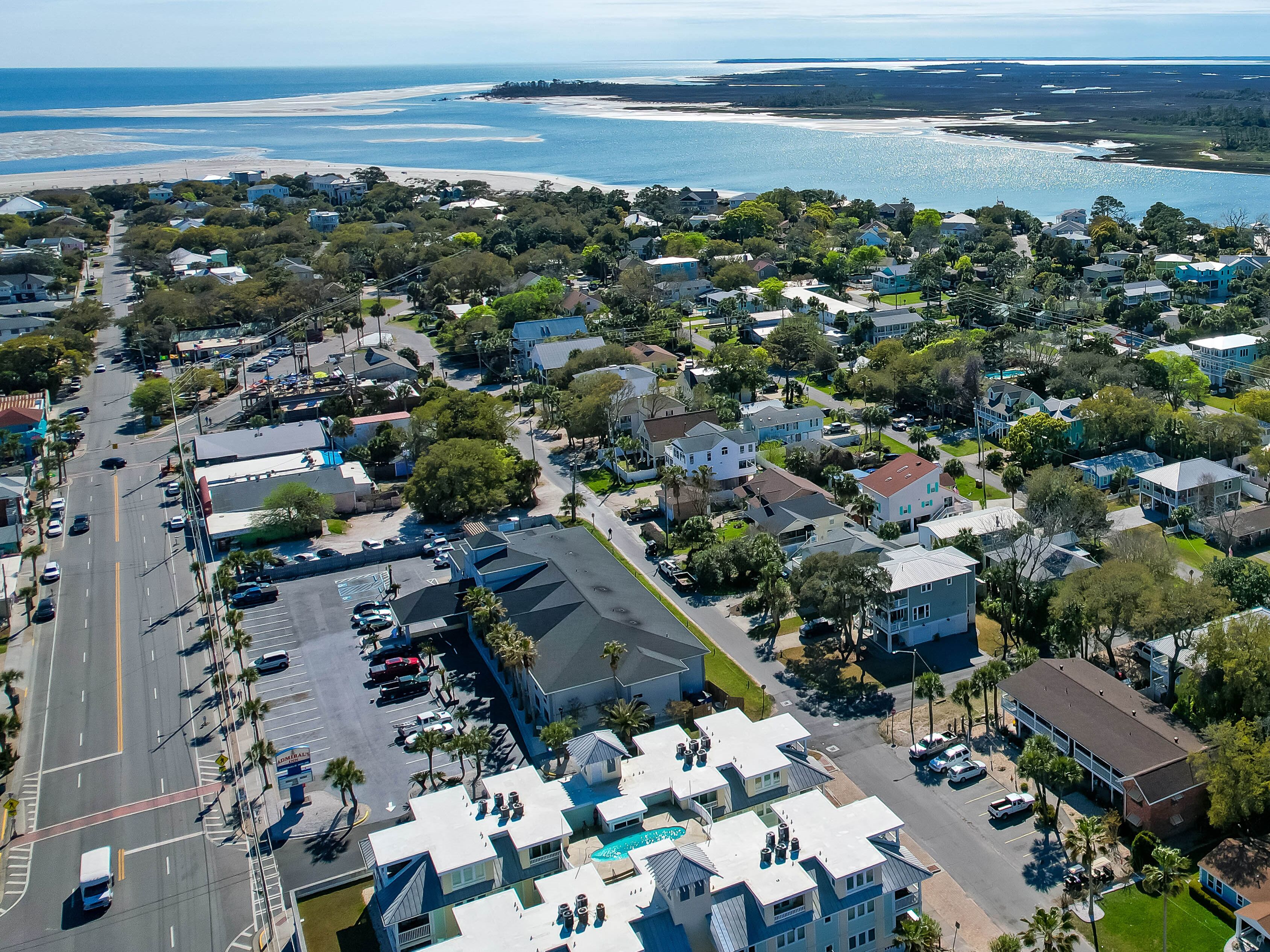 An aerial view of a coastal residential area with houses, streets, and a beach.