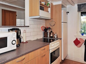 A compact kitchen with a microwave, stove, and wooden cabinets.