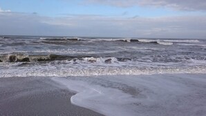 Una playa con olas y un cielo nublado.