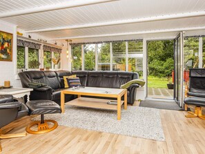 A modern living room with a leather sofa, wooden coffee table, and a glass door leading to a garden.