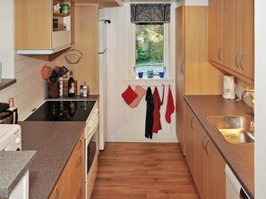 A compact kitchen with wooden cabinets, a built-in oven, and a window with a view. - 6 Person Holiday Home in Ulfborg (Ulfborg)