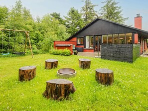 A modern house with a red exterior, a black roof, and a wooden deck with five stools. - 6 Person Holiday Home in Ulfborg (Ulfborg)