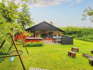 A house with a patio, a swing set, and a garden. - 6 Person Holiday Home in Ulfborg (Ulfborg)