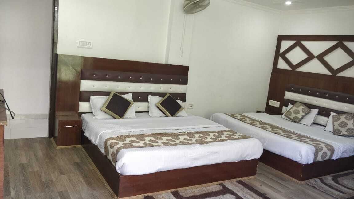 A hotel room with two beds, each with a wooden headboard and patterned bedspreads.