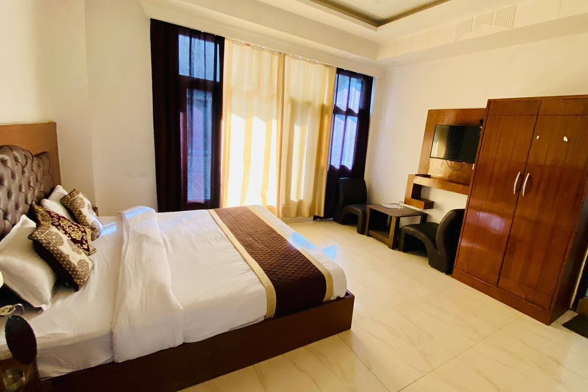 Habitación de hotel con una cama grande, un escritorio, un armario y un televisor.