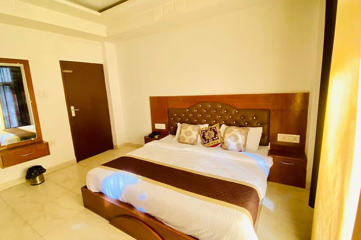 Una habitación de hotel con una cama grande, un cabecero de madera y una mesita de noche con una lámpara.