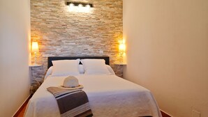 Un lit bien fait, avec une couette blanche et des oreillers, un chapeau décoratif et un plaid en tissu tissé.
