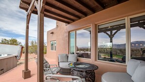 Un patio al aire libre con una zona de estar techada, un pozo de fuego y vistas del paisaje circundante.