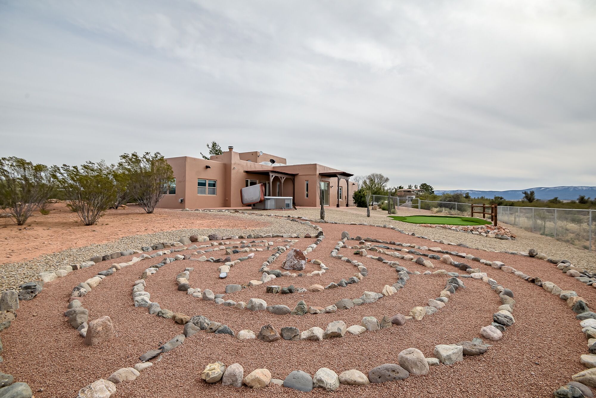 Una casa con jardín desértico que incluye un laberinto de rocas.