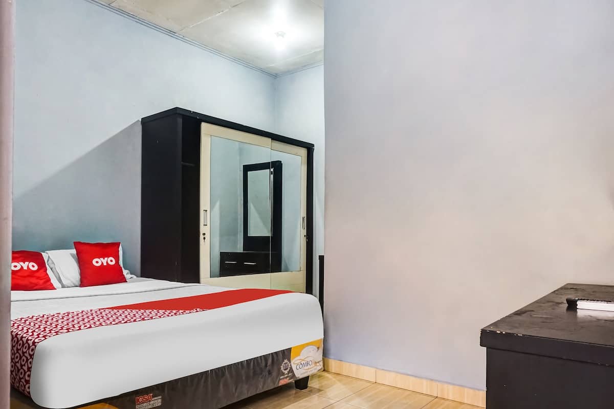 A hotel room with a bed, a wardrobe, and a small table.