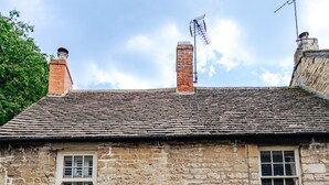 A stone building with a white door, two windows, and a sign reading "COLLEGE ROW". - Cozy Cotswold Dog Friendly Retreat  (Northleach)