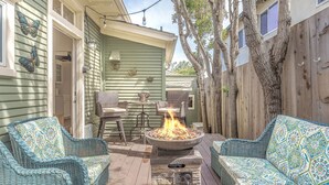 Eine Terrasse mit Korbmöbeln, einem Feuerkorb und einem Holzzaun.