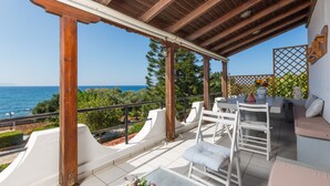A covered outdoor seating area with a view of the sea, white furniture, and a wooden pergola. - Seaside Family Villa for Weddings and Ceremonies (Rethymno)