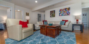 A living room with a beige sofa, a wooden coffee table, and a blue patterned rug. - Riverside Cottage with 2 Kayaks & Canoe (Lexington)