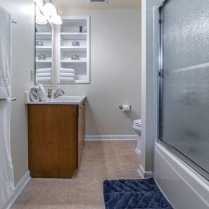 A bathroom with a wooden vanity, a mirror, a towel rack, and a shower area. - Riverside Cottage with 2 Kayaks & Canoe (Lexington)