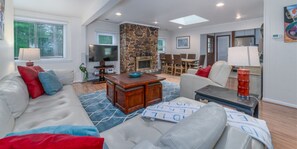 A living room with a stone fireplace, a television, and a dining area with chairs and a table. - Riverside Cottage with 2 Kayaks & Canoe (Lexington)