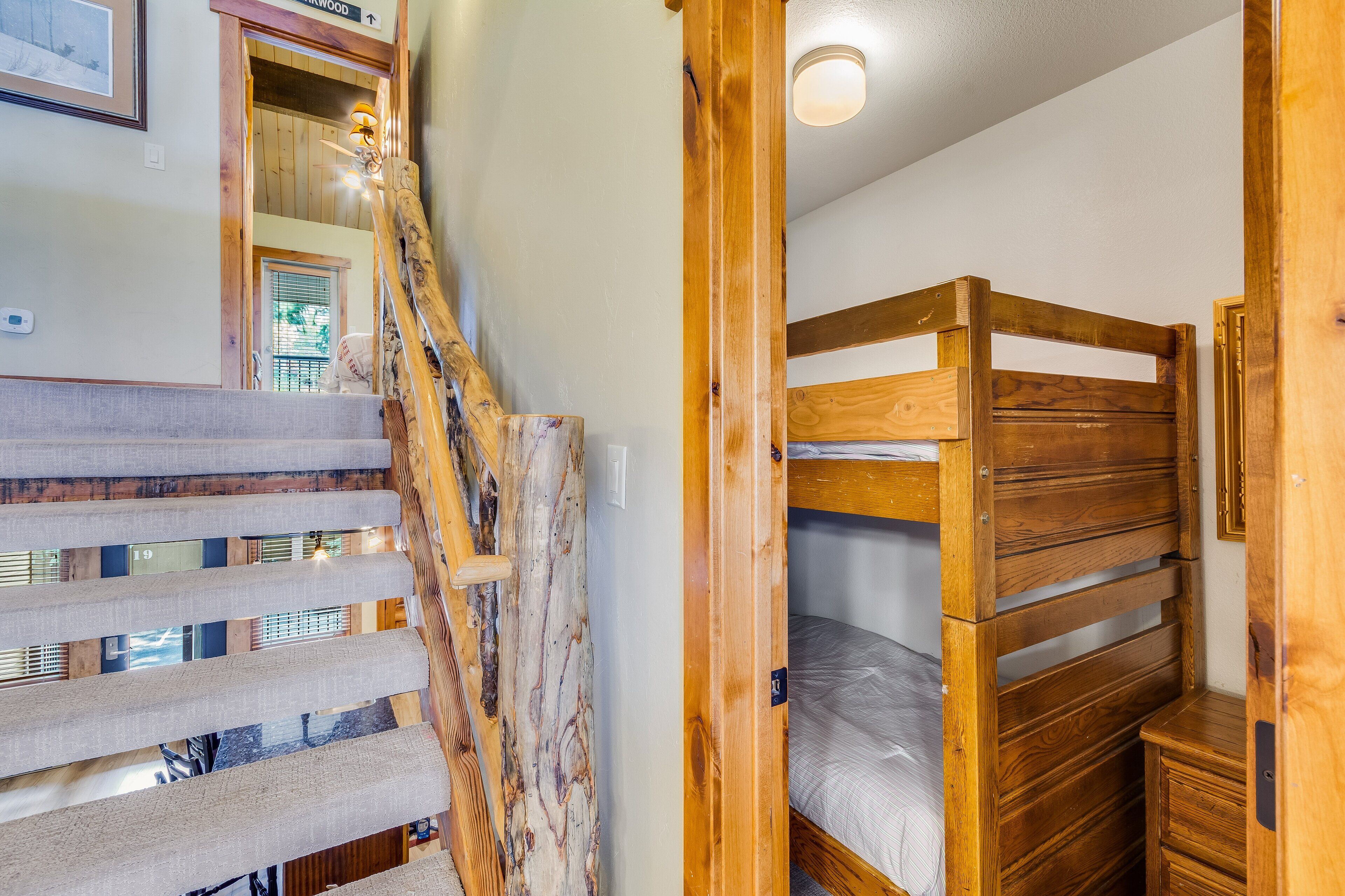 A wooden staircase with a handrail, a bunk bed, and a small wooden cabinet.