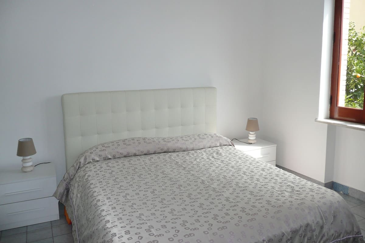A bedroom with a bed, two bedside tables, and a window.